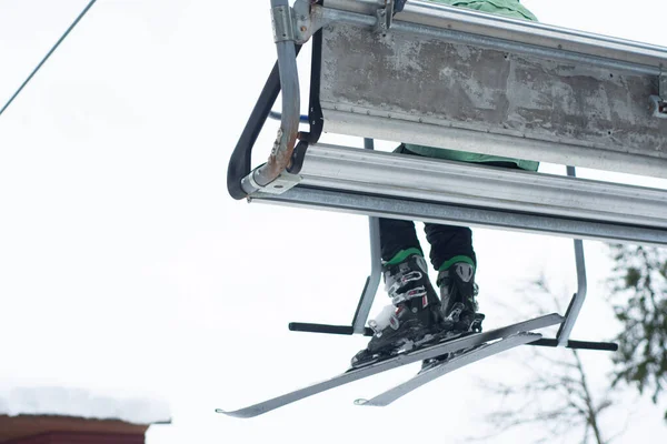 日当たりの良い冬の日にスキー場のリフトでスキー場に登る人々. — ストック写真