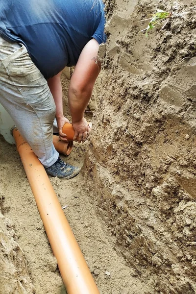 L'appaltatore installa una fogna in un fosso e conduce il tubo a — Foto Stock