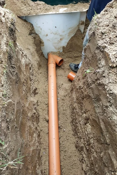 The contractor installs a sewer in a ditch and leads the pipe to