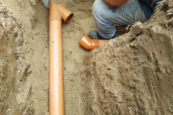 Fornitura di un tubo fognario ad una sump da parte di un mastro fabbro nel co — Foto Stock