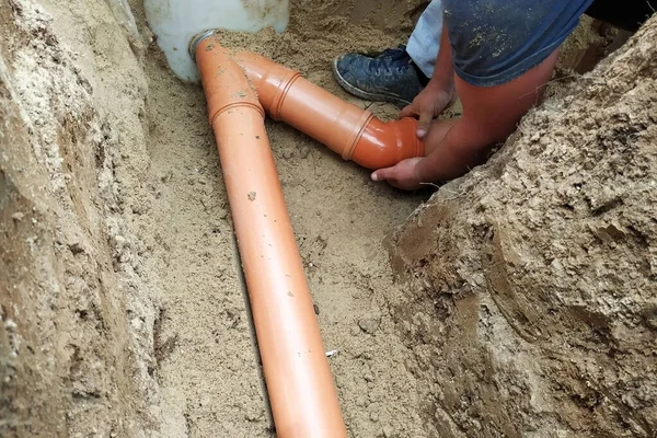 A locksmith supplies a sewer pipe to the sump. — Stock Photo, Image