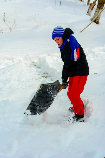 Limpeza de neve no inverno, o menino pás neve . — Fotografia de Stock