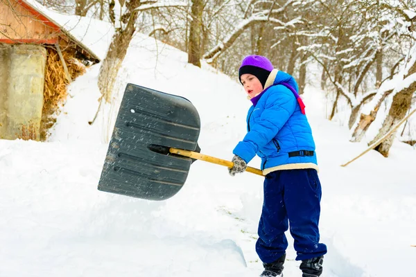 Depois de neve pesada, o menino limpa a neve com uma pá . — Fotografia de Stock