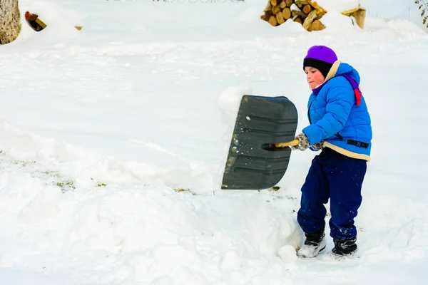 Menino com pá grande remove neve depois de uma tempestade de neve . — Fotografia de Stock