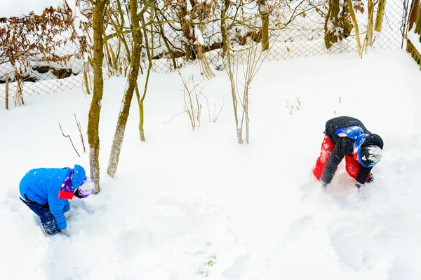 Zwei Brüder spielen Schneebälle in der Nähe ihres Hauses. — Stockfoto