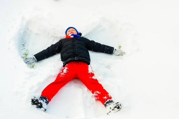 Egy jóképű fiú télen egy angyalt ábrázol a lábán.. — Stock Fotó