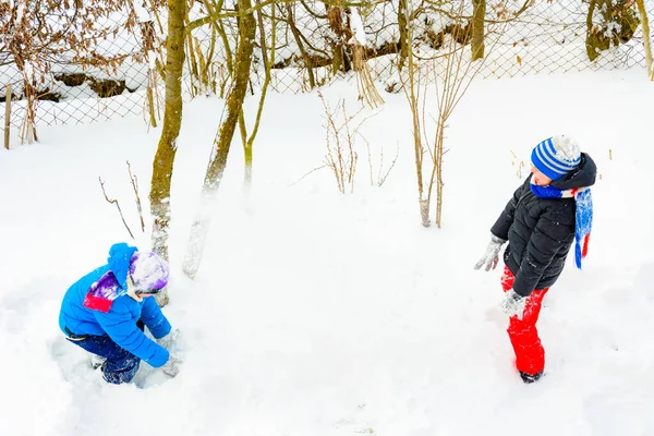 Dois irmãos jogando bolas de neve perto de sua casa . — Fotografia de Stock