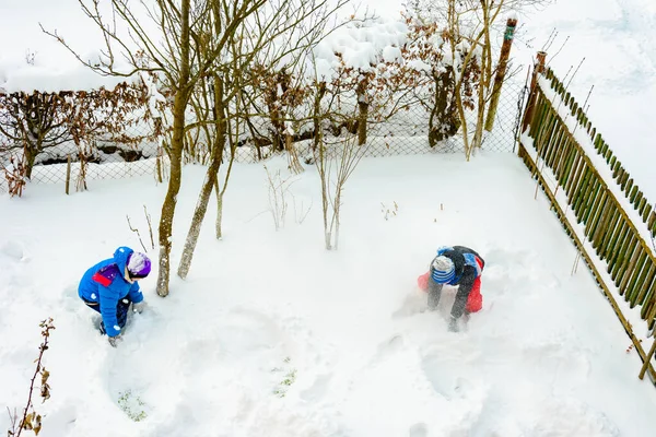 Dois irmãos jogando bolas de neve perto de sua casa . — Fotografia de Stock