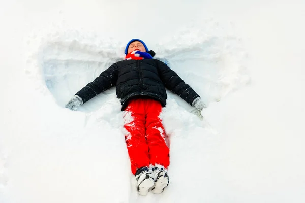 Ein hübscher Junge im Winter zeigt einen Engel auf seinem Fuß. — Stockfoto