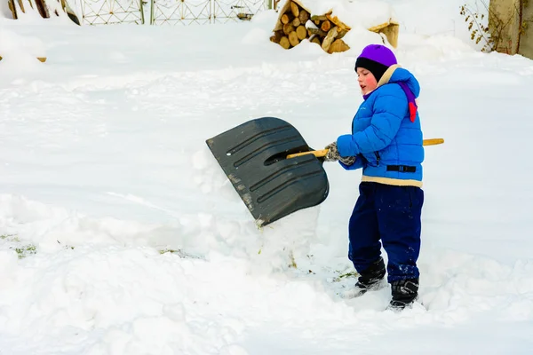 Menino com pá grande remove neve depois de uma tempestade de neve . — Fotografia de Stock