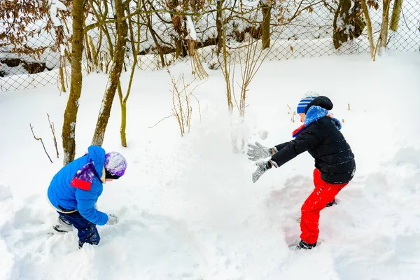 Dwóch braci grających w kulki śniegu w pobliżu domu. — Zdjęcie stockowe