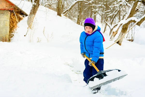 Nach starkem Schneefall räumt der kleine Junge den Schnee mit einer Schaufel. — Stockfoto