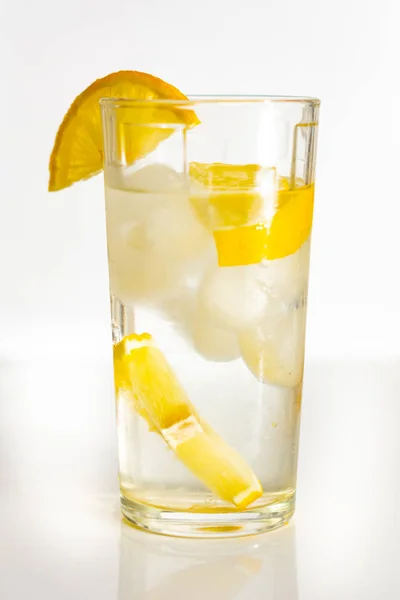 Un vaso de agua con hielo y rodajas de limón sobre un fondo blanco . —  Fotos de Stock
