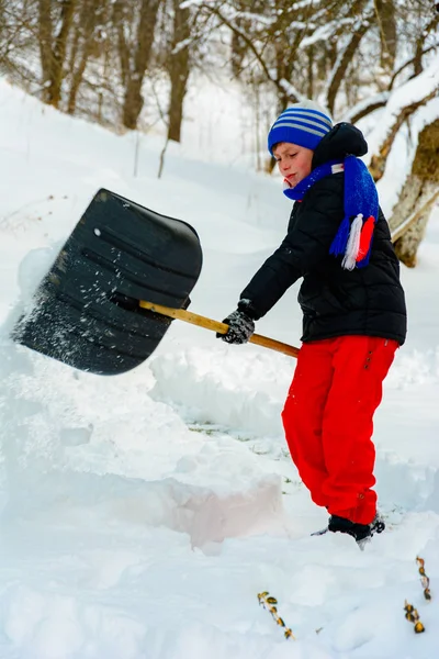 Limpeza de neve no inverno, o menino pás neve . — Fotografia de Stock