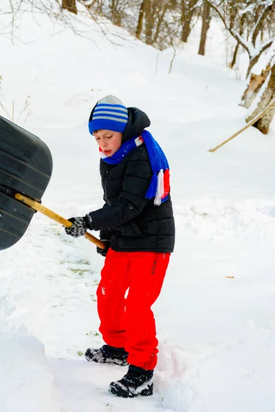 Limpeza de neve no inverno, o menino pás neve . — Fotografia de Stock