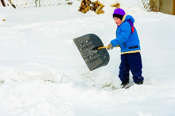 Menino com pá grande remove neve depois de uma tempestade de neve . — Fotografia de Stock