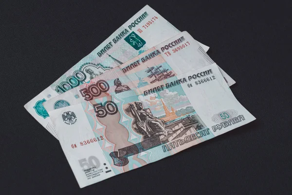 Russische bankbiljetten met een waarde van 500, 1000 en 50 duizend bevinden zich op een zwarte achtergrond.. — Stockfoto