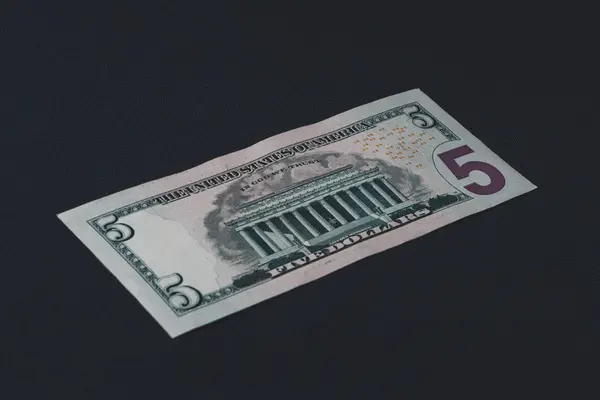 The American five dollars lie on the back on a black background. — Stock Photo, Image