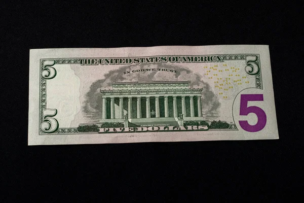 The American five dollars lie on the back on a black background. — Stock Photo, Image