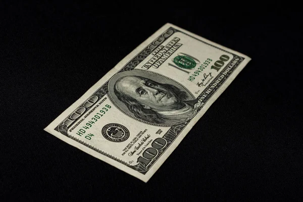 Sto amerykańskich dolarów leży na czarnym tle, wolne miejsce na inskrypcję. — Zdjęcie stockowe