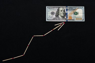 Beyaz kibrit çöpü oku doların siyah arka planda yükseldiğini gösteriyor.