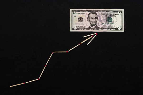 A seta branco matchstick mostra o dólar subindo em um fundo preto . — Fotografia de Stock