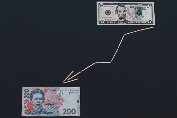 Ukrainian hryvnia and US dollar with arrow on black background. — Stock Photo, Image