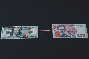 Ukrainian hryvnia and US dollar on black background.