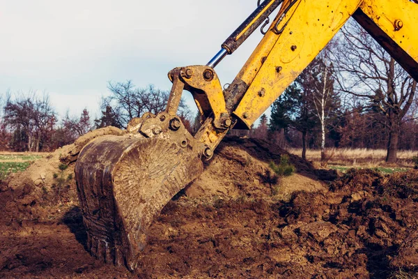 De graafmachine ontruimt de grond om de weg in privaat gebied te plaveien. — Stockfoto