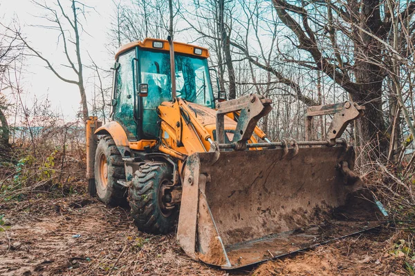 Gravemaskinen arbejder i skoven med at rydde skoven . - Stock-foto