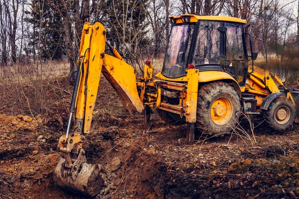 Una excavadora amarilla en el bosque cava un pozo para un estanque . —  Fotos de Stock