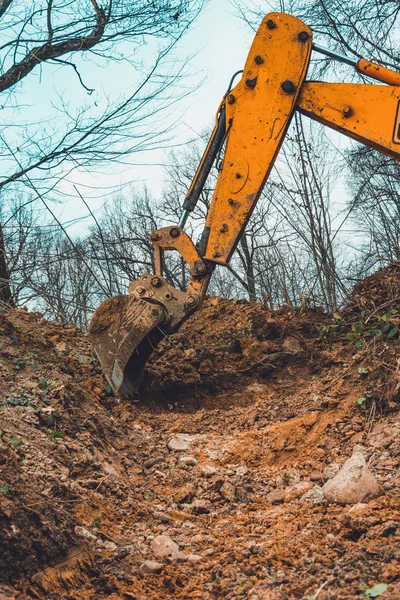 Uma escavadora amarela na floresta cava um poço para uma lagoa . — Fotografia de Stock