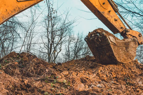 Fondo de cubo de excavadora con suelo en el bosque y el fondo del cielo . —  Fotos de Stock