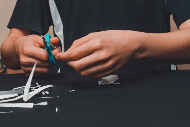 Çocuk elleri ve makasıyla beyaz kağıdı katlıyor ve kesiyor..