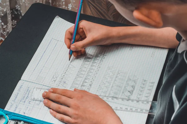 Pequeno estudante entediado lição de casa em um caderno da escola para desenhar . — Fotografia de Stock