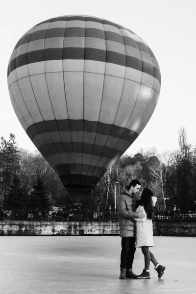 Bruid en bruidegom tegen de achtergrond van een bevroren meer en een ballon vliegen in een stadspark. — Stockfoto