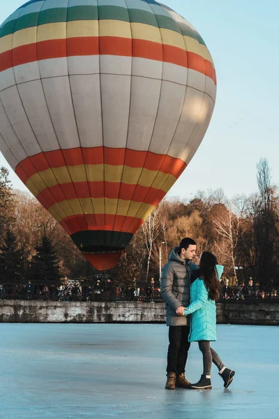 Nevěsta a ženich na pozadí zamrzlého jezera a balón létající v městském parku. — Stock fotografie