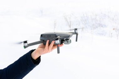 Genç bir adam kışın ormana bir dron fırlatıyor..