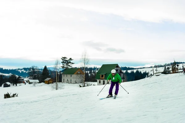 Jovem de casaco verde e calças roxas esqui . — Fotografia de Stock