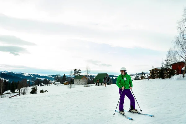 Junger Mann in grüner Jacke und lila Hose beim Skifahren. — Stockfoto