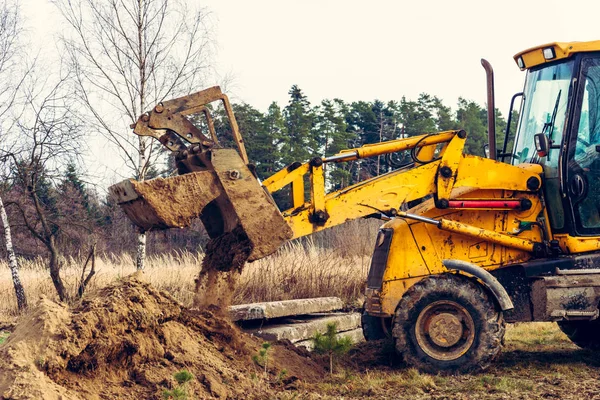 Uma antiga escavadora amarela ajuda a montar a estrada na aldeia . — Fotografia de Stock