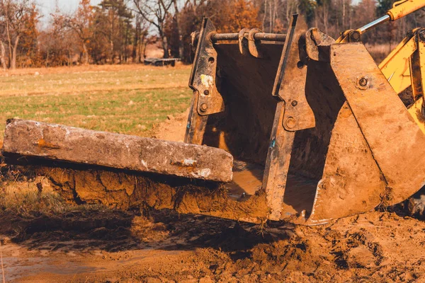 A escavadora amarela transporta lajes de concreto no campo . — Fotografia de Stock