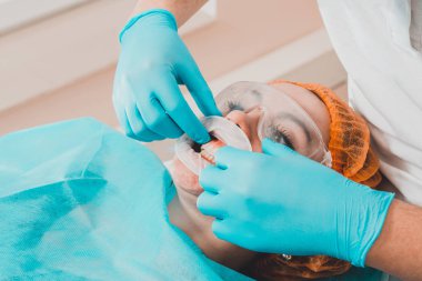 Genç bir dişçi diş kliniğinde ağız genişletme aleti çekiyor..