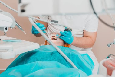 Hasta dişçide ultrasonik diş temizleme prosedürü hakkında dişçiye gider..