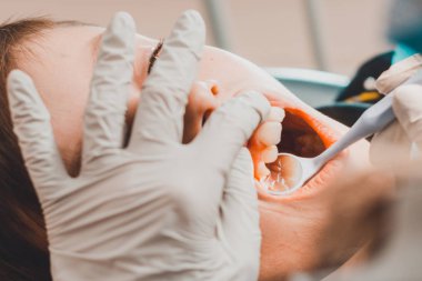 Çocuk bir ortodontist tarafından muayene edildi, ağzını iyice açtı ve dişçi dişlerini muayene etti..