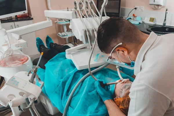 Hasta diş koruyucusuyla diş sandalyesine oturur, doktor tartartarı çıkarır..