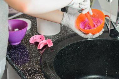 İlk izlenim, ortodontist hastanın ağzını ölçmek için pembe bir karışım hazırlar.