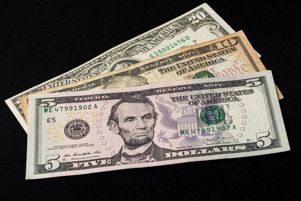 Beş, on ve yirmi dolarlık banknotlar siyah arka planda yatıyor.. — Stok fotoğraf