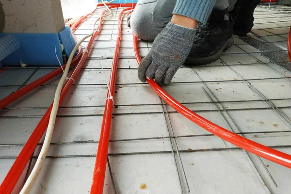A mester csöveket fektetett a padlóra fűtésre és padlófűtésre.. — Stock Fotó