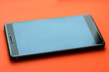 Smartphone, front and back side of smartphone with modern touch screen isolated on orange background.